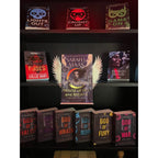 Curio Clip-On Angel Wings attached to a Curio Candy Floating Book Display Hanger, fitting snugly on a bookshelf framed by dark romance and spicy paranormal books including Sarah J. Maas, Rina Kent, and Navessa Allen.