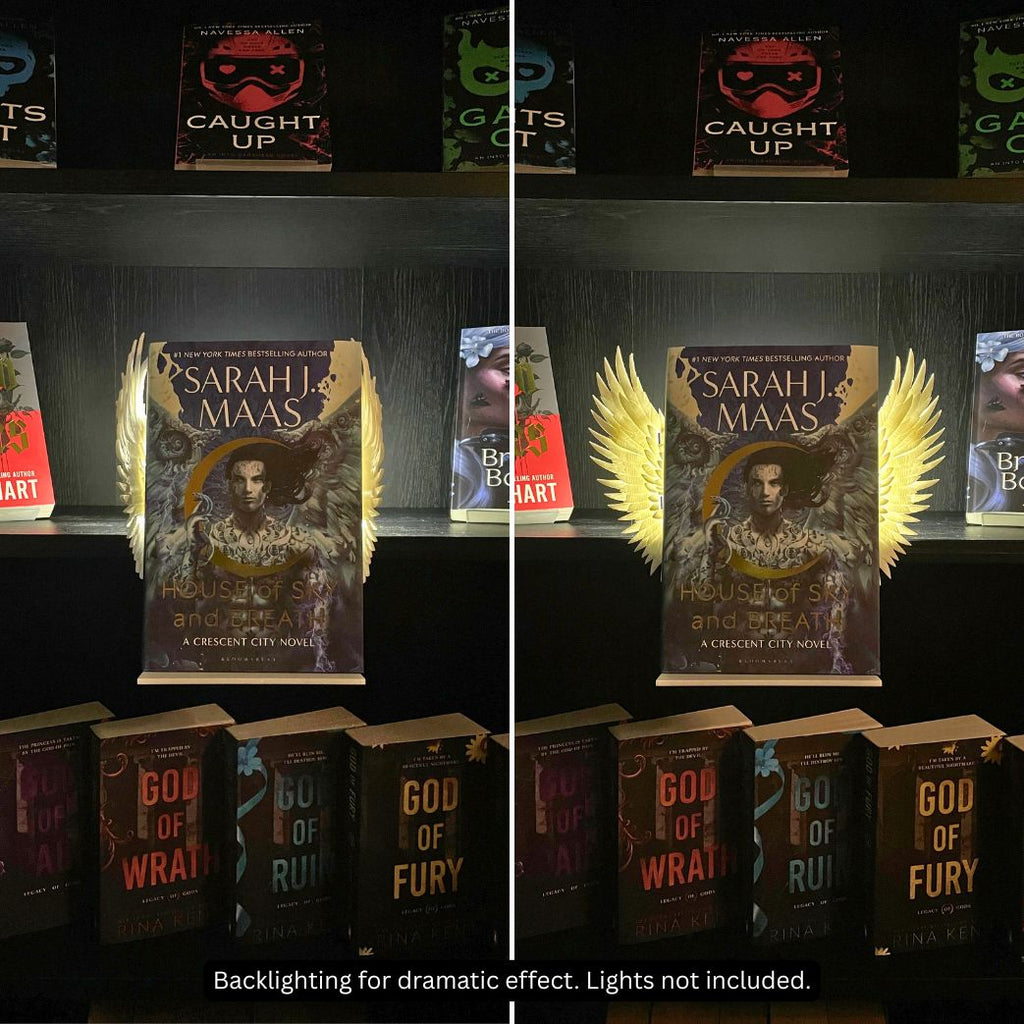 Side-by-side comparison of closed and open Curio Clip-On Angel Wings attached to a Curio Candy Floating Book Display Hanger, backlit on a dark romance bookshelf featuring Sarah J. Maas.