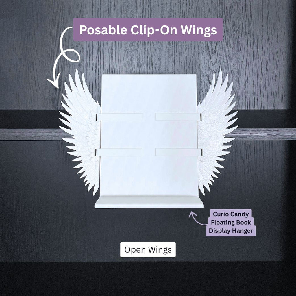 Curio Clip-On Angel Wings shown in the open position attached to a Curio Candy Floating Book Display Hanger mounted on a bookshelf.