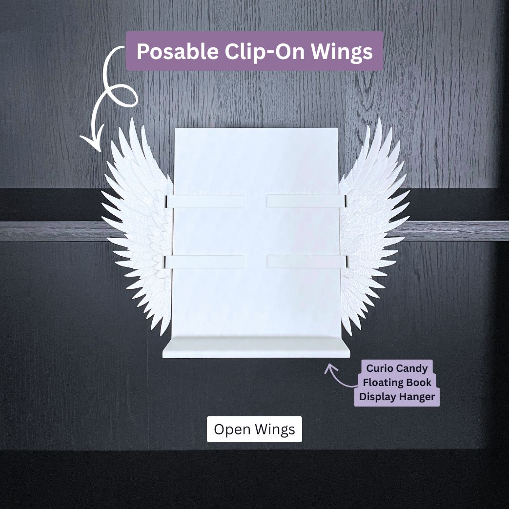Curio Clip-On Angel Wings shown in the open position attached to a Curio Candy Floating Book Display Hanger mounted on a bookshelf.