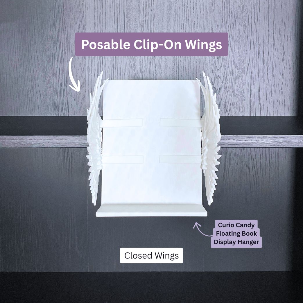 Curio Clip-On Angel Wings shown in the closed position attached to a Curio Candy Floating Book Display Hanger mounted on a bookshelf.
