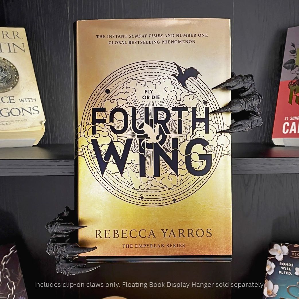 Curio Candy Curio Clip-On black dragon claws accessory attached to a Curio Candy floating book display hanger, holding a copy of "Fourth Wing" by Rebecca Yarros on a black bookshelf.
