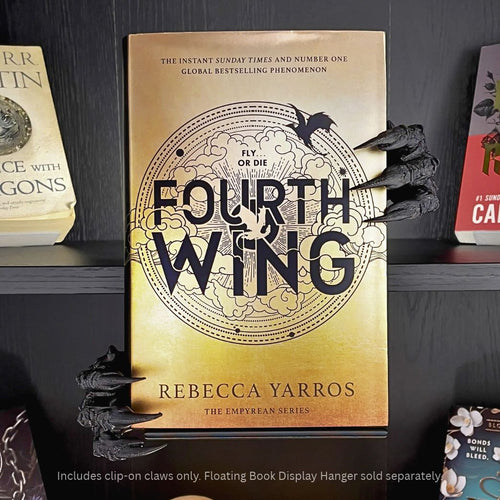 Curio Candy Curio Clip-On black dragon claws accessory attached to a Curio Candy floating book display hanger, holding a copy of "Fourth Wing" by Rebecca Yarros on a black bookshelf.