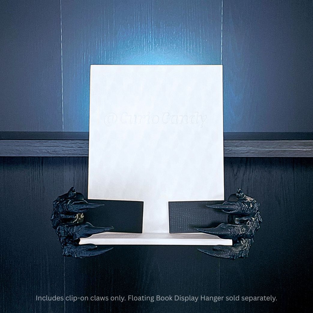 Black 3D printed Dragon Claws Curio Clip-Ons attached to a white Curio Candy Floating Book Display Hanger against a dark wood background with blue top backlighting.