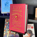 Curio Candy black floating book display hanger showing Alice in Wonderland classic hardcover on black IKEA Billy bookcase.